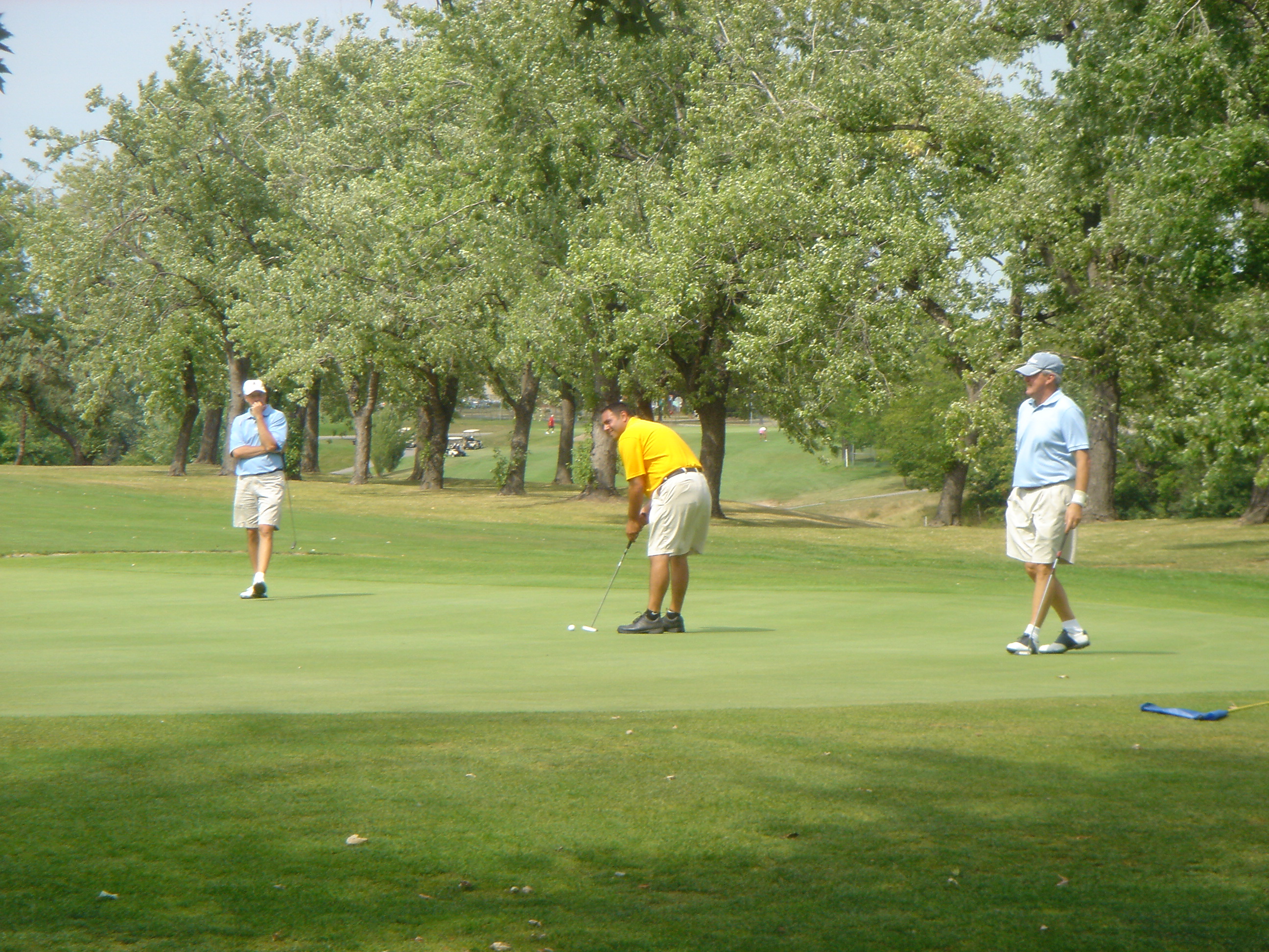 Tom Gantress and Jim Mohan watch Scott Yudess putt on 18 green